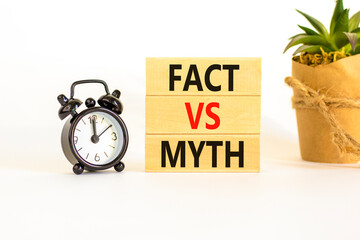 Fact vs myth symbol. Concept words Fact vs myth on wooden blocks on a beautiful white table white background. Black alarm clock. Business, finacial and fact vs myth concept. Copy space.