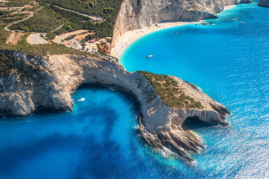 Aerial view of blue sea, mountains, white sandy beach at sunrise in summer. Porto Katsiki, Lefkada island, Greece. Beautiful landscape with sea coast, yacht, rocks, azure water, green forest. Top view
