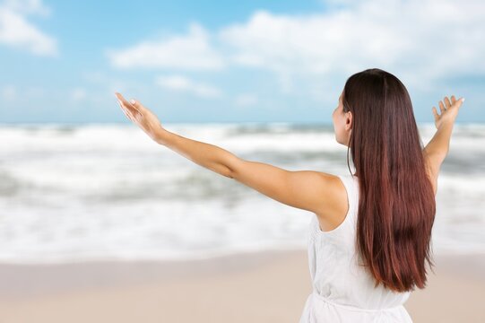 Healthy woman standing on the beach. Freedom girl dancing and daydreaming at beach during summer vacation.
