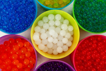 Orbeez toy, close-up. Hydrogel balls or Water beads in plastic cups, top view. Flexible gel balls...
