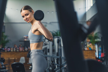Fototapeta na wymiar Indoor gym shot of a proud strong caucasian young adult woman at the gym, lifting barbell. Fitness concept. High quality photo