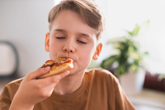 The Guy With Pleasure Eats A Delicious Pizza In The Kitchen At Home.