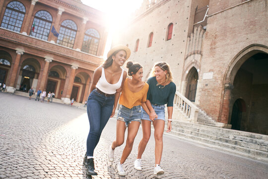 Three mixed race female friends having fun at the city in summer vacations. Women laughing together outdoors