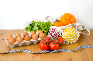 Vegetables,fruit and eggs near dumbbells and measuring tape. Sport and diet cocnept. HEalthy food