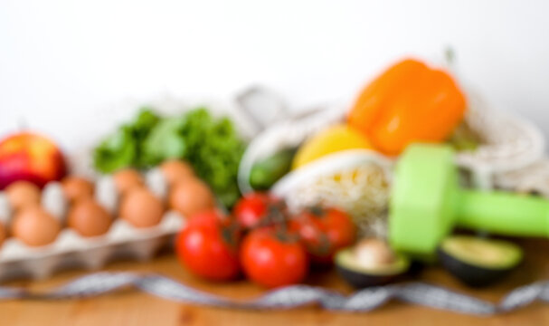 .Blurred background with place for text.Defocused image for text with Vegetables anf fruit near dumbbells and measuring tape. Sport and diet cocnept. HEalthy eating habits