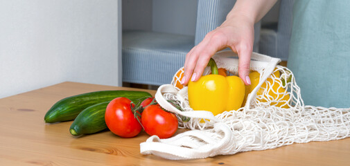 Closeup of a woman's hand getting pepper from eco-friendly shopper. Sustainable shopping concept.Healthy eating