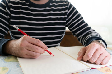 hombre escribiendo en un cuaderno rayado con una pluma y un lapiz