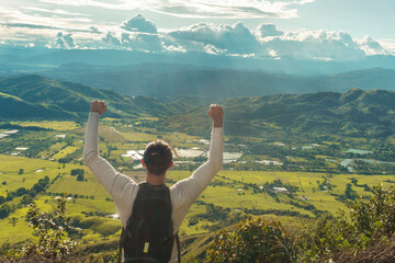 A man at the top of the mountain with hands up