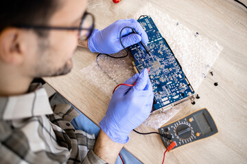 An expert repairing electronic device and checking voltage of motherboard in computer service.