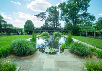 Bronx, NY - USA - June 4, 2022 a view of the Aquatic Garden at Wave Hill. A reflective pool with aquatic plants, hedges and pergolas. Wave Hill is an estate in the Hudson Hill section of Riverdale.