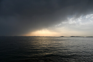 Waves on the sea with dramatic clouds above at sunset. Stormy weather at the sea, view from a boat. Rainy summer day. 