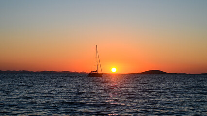 The silhouette boat at sunset. The boat on the sea. Fishing boat is running on deep blue sea.