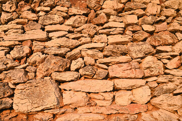 Dry stone wall, close up. Stone wall near the house in countryside. A traditional dry stone wall in the field at sunset. Medieval stone wall pattern.