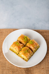 Pistachio baklava on a white plate.A plate baklava on bright background