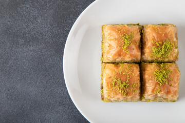 Pistachio baklava in white plate on dark background