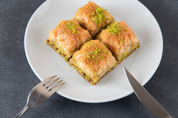 Pistachio baklava on a white plate.A plate of traditional baklava on a dark background