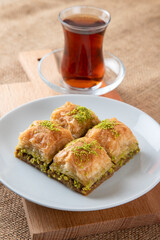 Pistachio baklava on a white plate with Turkish tea.