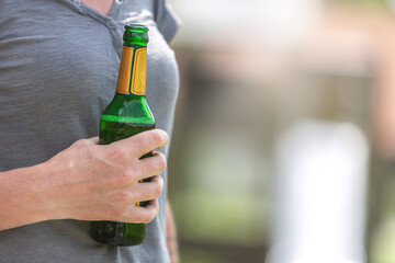 Close-up portrait of a woman holding a beer bottle in her hand. Text space