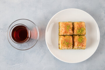 Pistachio baklava on a white plate with Turkish tea