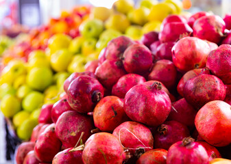 Heap of fresh eco pomegranates for sale in market, background of pomegranate fruits