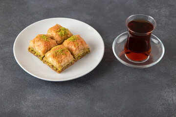 Pistachio baklava on a white plate with Turkish tea	