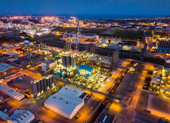Fototapeta premium Aerial view of illuminated chemical process plant near Spanish town of Salou at twilight