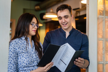 Happy couple two people man and woman standing at home or agency holding brochure reading content...