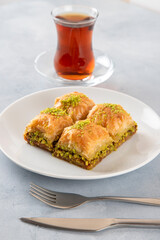 Baklava pistachio on a white plate with Turkish tea
