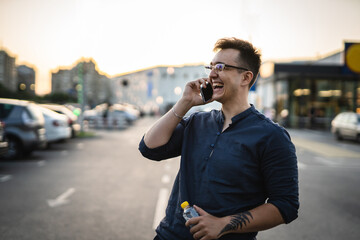 One man happy caucasian male standing at the parking lot in front of the market making a phone call...
