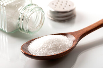Monosodium glutamate in wooden spoon on white background.