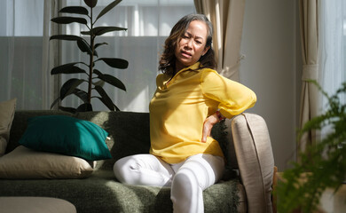 Obraz premium Unhappy mature woman touching, massaging back, suffering from backache. Health care, pain, stress, age and people concept.