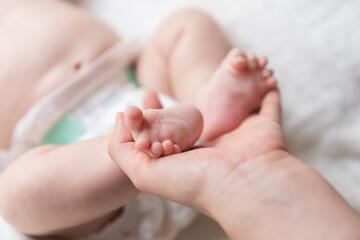 Fototapeta na wymiar 赤ちゃんの足　お母さんの手