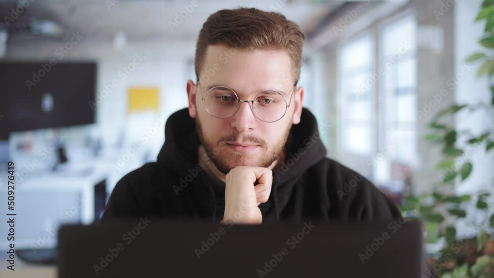 Poster thoughtful professional programmer sitting and pondering in front of laptop monitor in office. skill