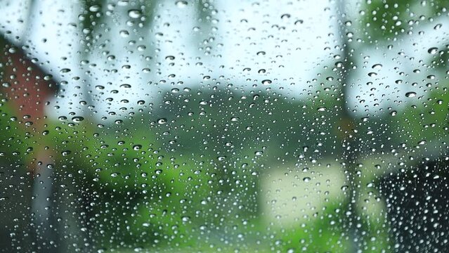 窓ガラスに降る雨の水滴　田舎の住宅地　梅雨　イメージ