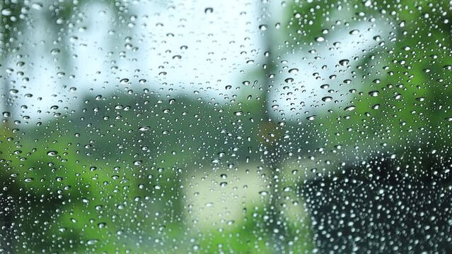 窓ガラスに降る雨の水滴　田舎の住宅地　梅雨　イメージ