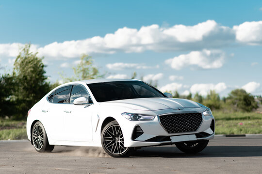 White Genesis G70 unfolds in motion against the backdrop of nature. Executive class car produced by the South Korean company Hyundai Motor. Russia, Rostov-on-Don 16may2022