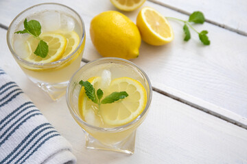 Summer Refreshing Lemonade on white background with yellow lemons and mint fresh leaves, top view, space for copy