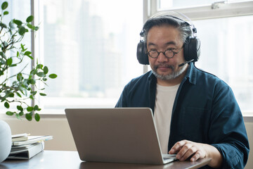 Asian middle aged man sitting at home working on video call. Work from home concept