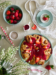 Strawberry pie. Buns with strawberries in the form of one large pie in strawberry sauce. Summer photo of homemade cakes in a round plate with strawberries decorated with flowers. Strawberry jam 