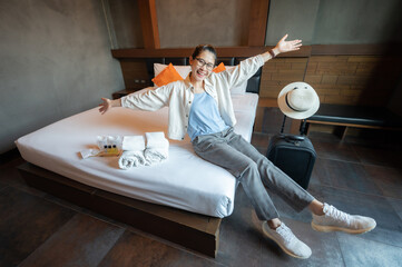 Happiness Asian tourist sitting on bed in hotel bedroom after check in. Conceptual of travel and...