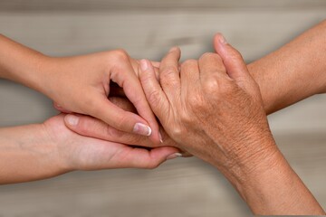 Fototapeta premium Support hands. young woman holding a senior man's hands in comfort. Female carer holding hands of senior man