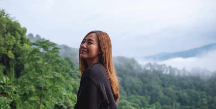 Portrait image of a young woman with a beautiful foggy mountain and nature view