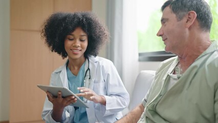 African American female medical doctor using digital tablet explain the symptoms to the patient after treatment or talking with old man patient in the hospital.
