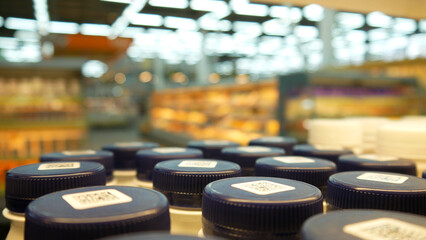 Close-up of many bottles of yogurt with dark blue caps on a store shelf