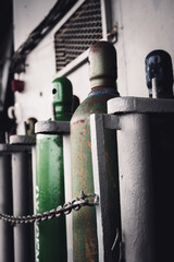 Compressed gas cylinders being stored vertically secured by a metal chain.