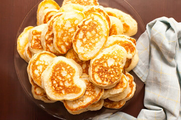 A stack of buttered pancakes on a white porcelain plate. Blurred background with spring flowers.