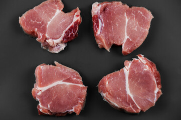 Raw pork against a gray background. Four portioned pieces of pork shoulder ready for further cooking or marinating. Food, ingredients. Selective Focus
