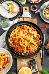 Assortment of Italian pasta with traditional sauces for dinner on dark background. Homemade food concept