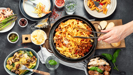 Assortment of Italian pasta with traditional sauces for dinner on dark background. Homemade food concept