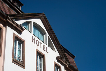 Closeup of .Hotel sign on building facade in the street on blue sky background